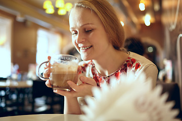 Image showing Girl is drinking latte in cafe.