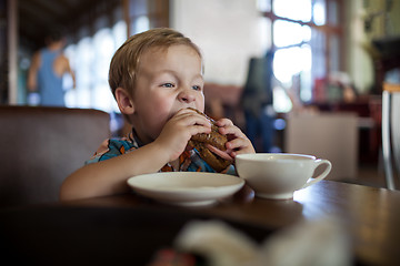 Image showing Little boy having sandwich in a cafe