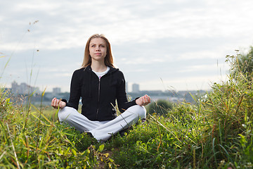 Image showing Young girl makes yoga exercises outdoors.