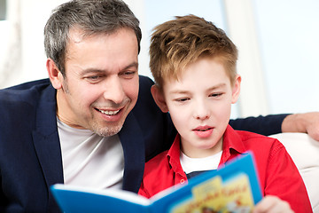 Image showing Dad and son reading a book at home