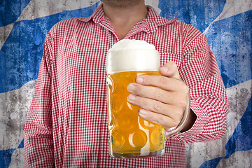 Image showing Man in traditional Bavarian shirt holds mug of beer