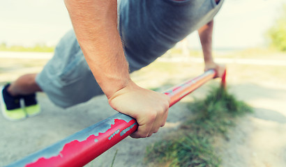 Image showing young man exercising on horizontal bar outdoors