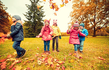 Image showing happy children playing with autumn leaves in park