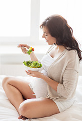 Image showing happy pregnant woman eating salad at home