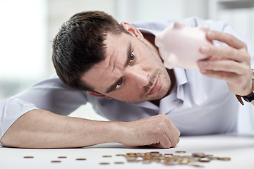 Image showing businessman with piggy bank and coins at office