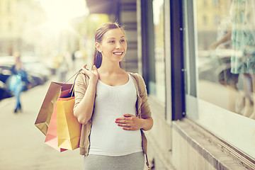 Image showing happy pregnant woman with shopping bags at city