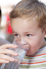 Image showing Little boy drinkng a glass of fresh water