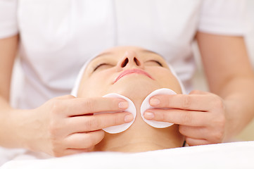 Image showing Cosmetician cleaning face using cotton pads