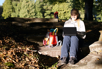 Image showing Young woman working outdoors on a laptop