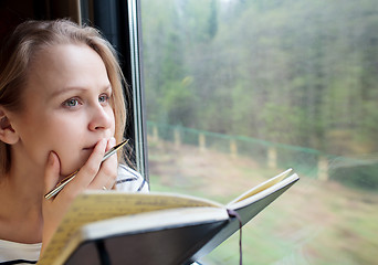 Image showing Young woman on a train writing notes