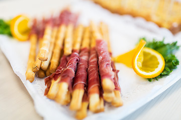 Image showing close up of grissini bread sticks with prosciutto