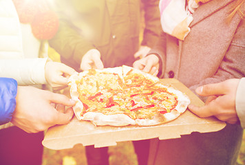 Image showing close up of friends hands eating pizza outdoors