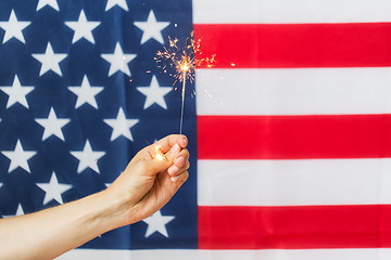 Image showing close up of hand with sparkler over american flag