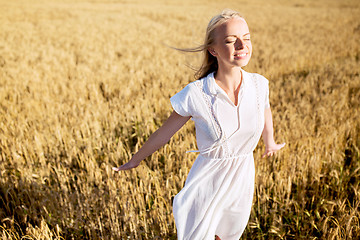 Image showing smiling young woman in white dress on cereal field