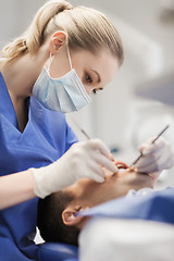 Image showing female dentist checking up male patient teeth