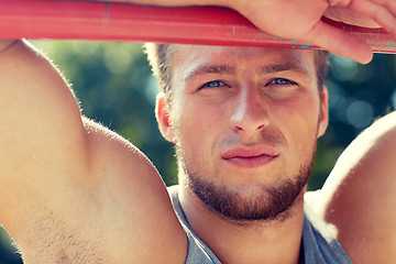 Image showing young man exercising on horizontal bar outdoors