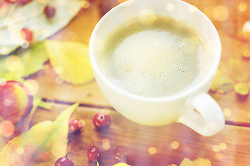 Image showing close up of coffee cup on table with autumn leaves