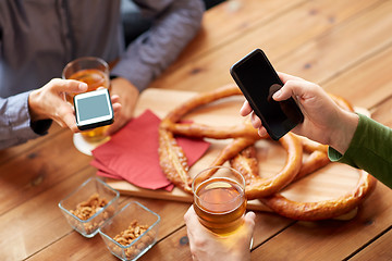 Image showing close up of hands with smartphones and beer at bar