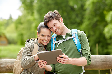 Image showing happy couple with backpacks and tablet pc outdoors