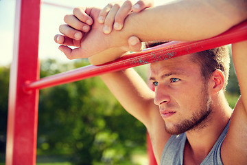 Image showing young man exercising on horizontal bar outdoors