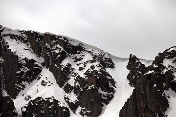 Image showing Rocks with snow cornice in gray day