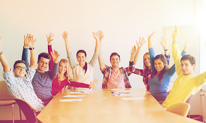 Image showing group of smiling students raising hands in office