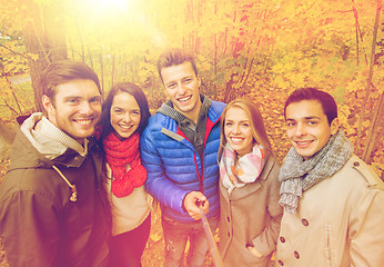 Image showing smiling friends taking selfie in autumn park