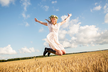 Image showing happy woman in wreath jumping on cereal field