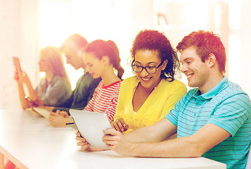 Image showing smiling students looking at tablet pc at school