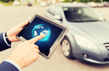 Image showing close up of male hands with tablet pc and car
