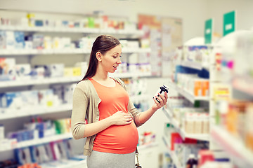 Image showing happy pregnant woman with medication at pharmacy