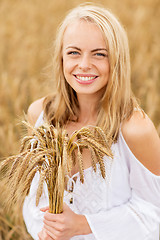 Image showing happy young woman with spikelets on cereal field