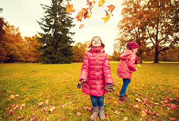 Image showing happy children playing with autumn leaves in park