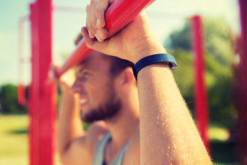 Image showing young man exercising on horizontal bar outdoors