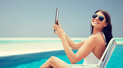 Image showing smiling woman with tablet pc sunbathing on beach