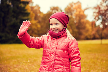 Image showing happy little girl waving hand in autumn park