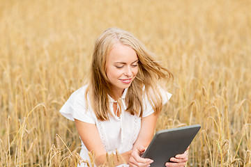 Image showing happy young woman with tablet pc on cereal field