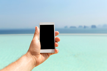 Image showing close up of male hand holding smartphone on beach