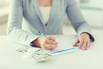 Image showing close up of hands with money filling tax form