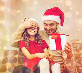 Image showing smiling father surprises daughter with gift box