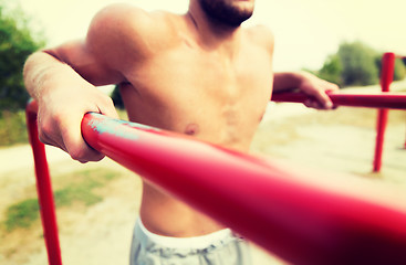 Image showing young man exercising on parallel bars outdoors