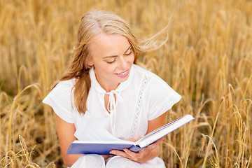 Image showing smiling young woman reading book on cereal field