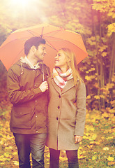 Image showing smiling couple with umbrella in autumn park