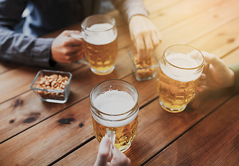 Image showing close up of hands with beer mugs at bar or pub