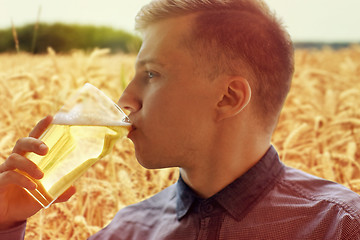 Image showing close up of young man drinking beer from glass