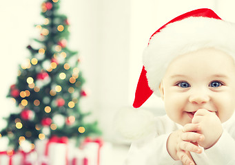 Image showing happy baby in santa hat over christmas tree lights