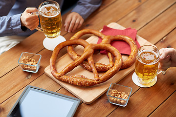 Image showing close up of man drinking beer with pretzels at pub