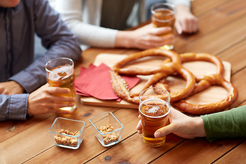 Image showing close up of men drinking beer with pretzels at pub