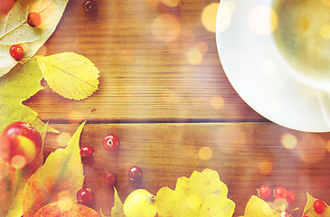 Image showing close up of coffee cup on table with autumn leaves