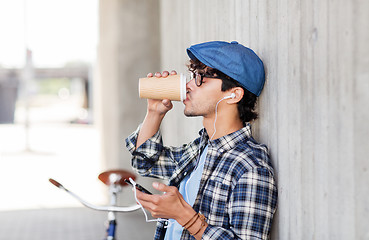 Image showing man with earphones and smartphone drinking coffee